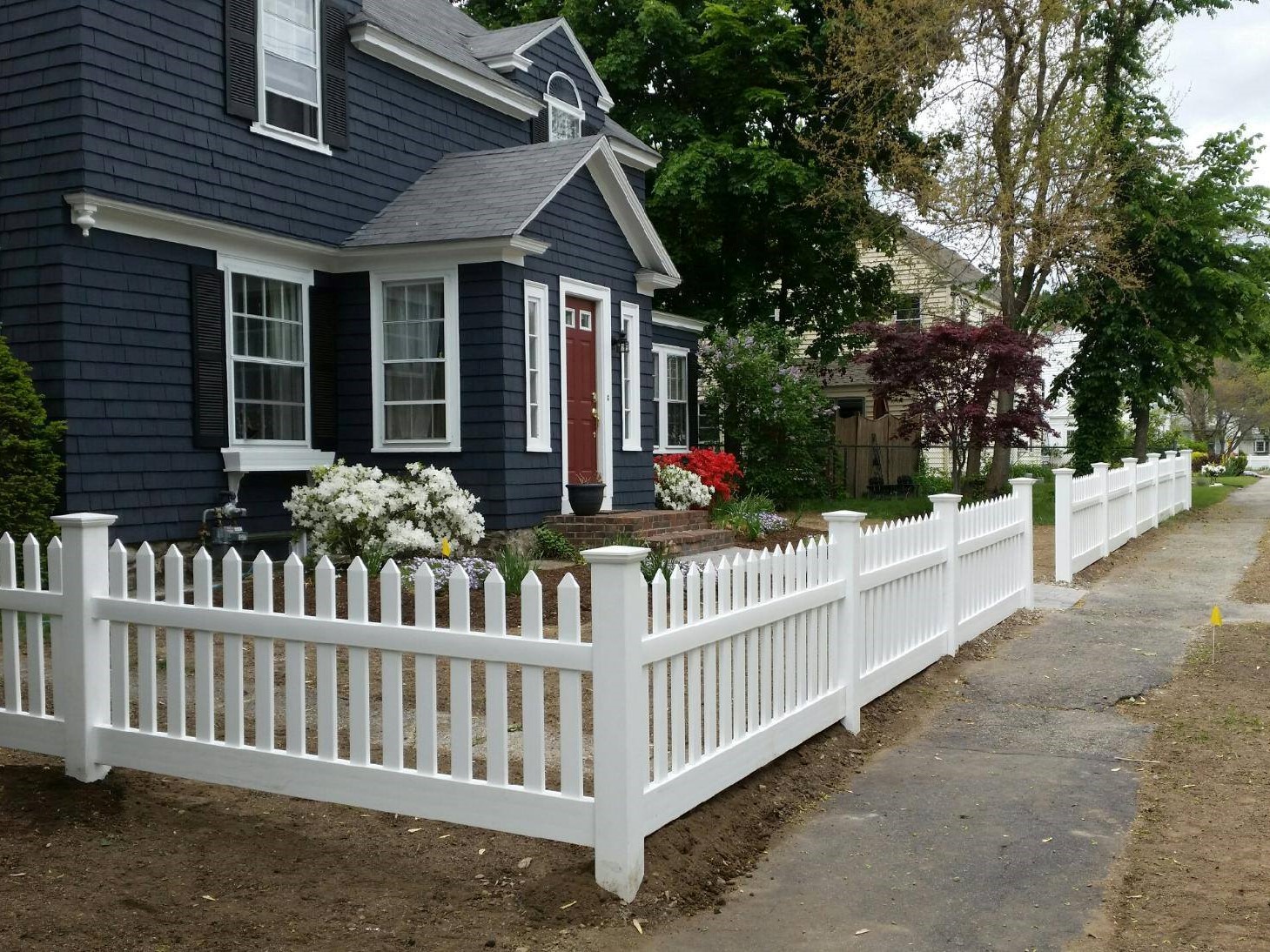 Photo of a white picket vinyl fence in a residential front yard.